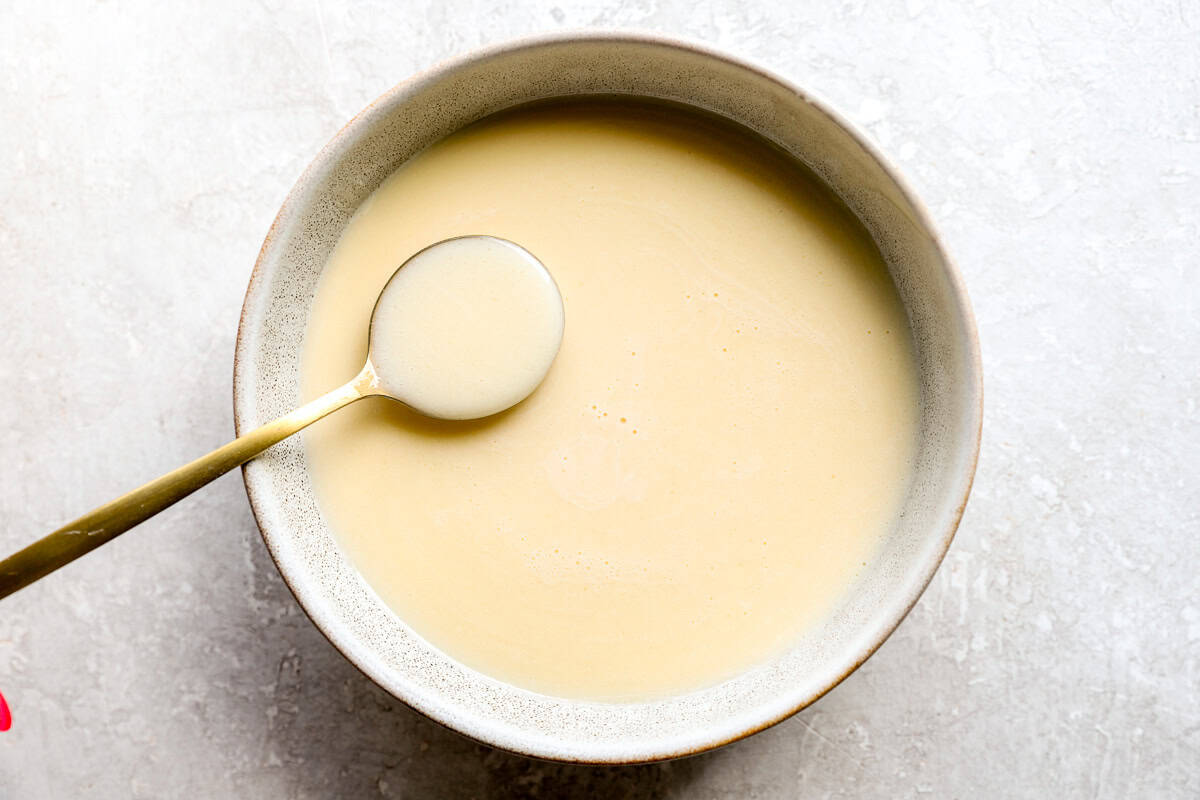 Silky smooth beurre blanc sauce in a serving bowl with a gold spoon.