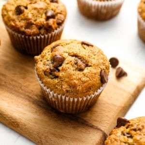 Closeup of fresh banana chocolate chip muffins on a wooden cutting board.
