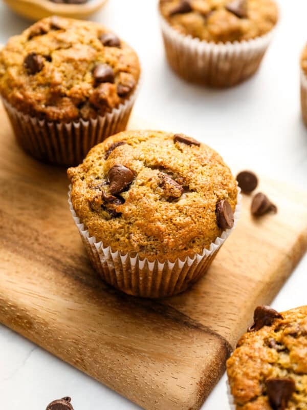 Closeup of fresh banana chocolate chip muffins on a wooden cutting board.