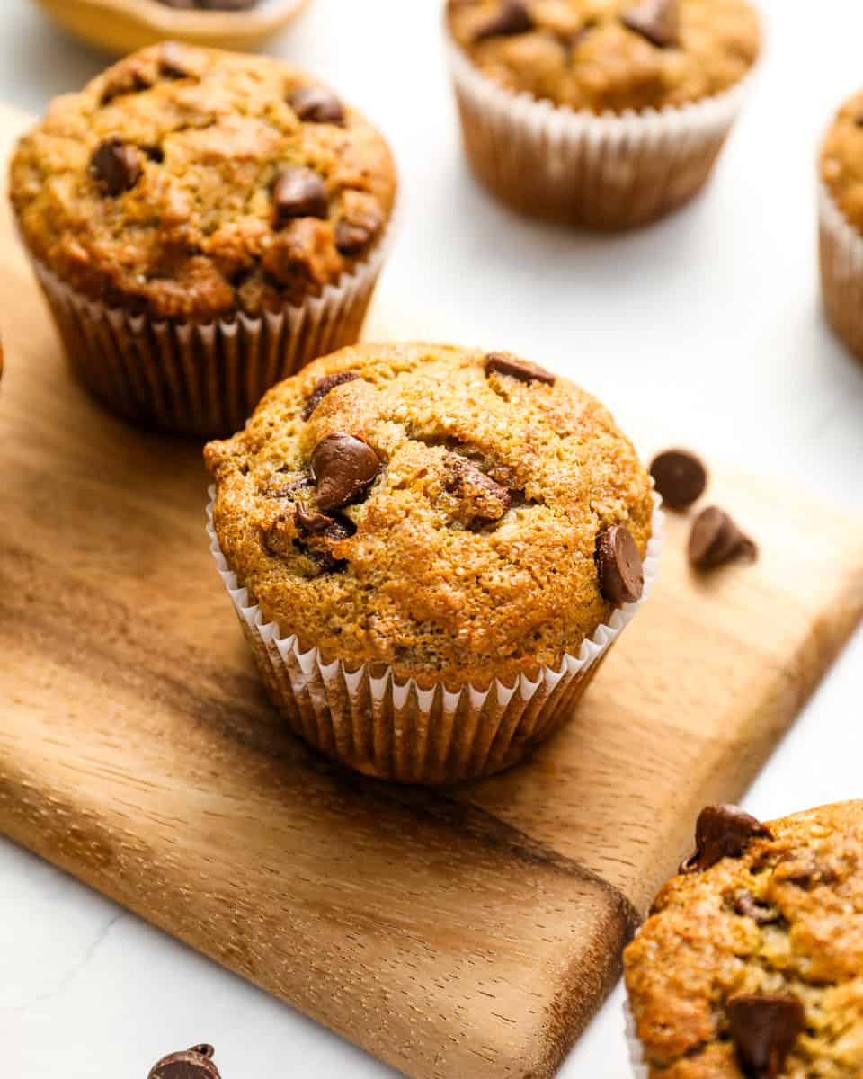 Closeup of fresh banana chocolate chip muffins on a wooden cutting board.