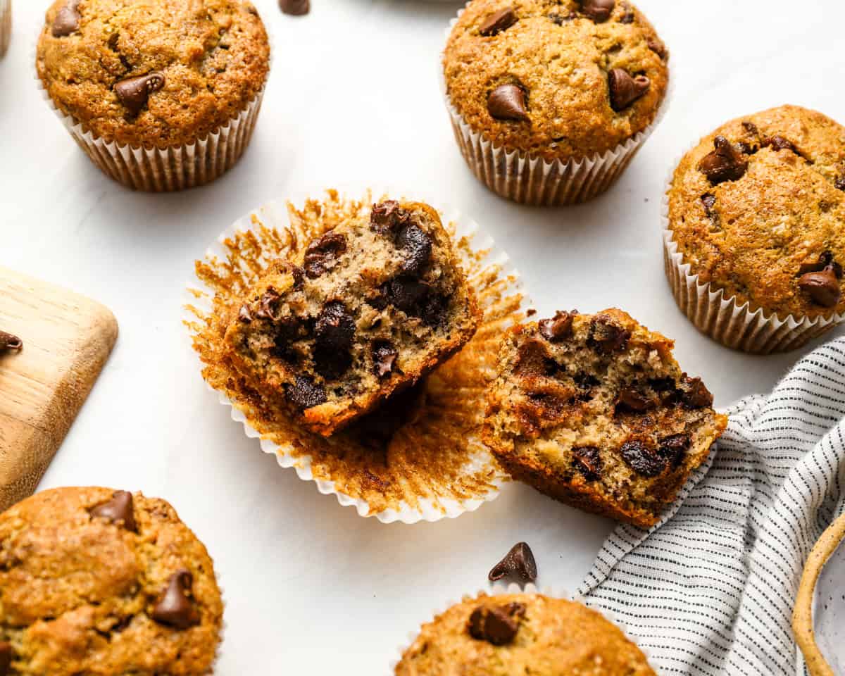 Close-up of one banana chocolate chip muffin broken in half, revealing a fluffy inside with melted chocolate chips.