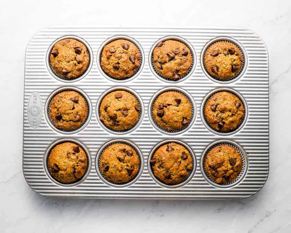 Fully baked banana chocolate chips muffins still in the muffin tin, fresh out of the oven.