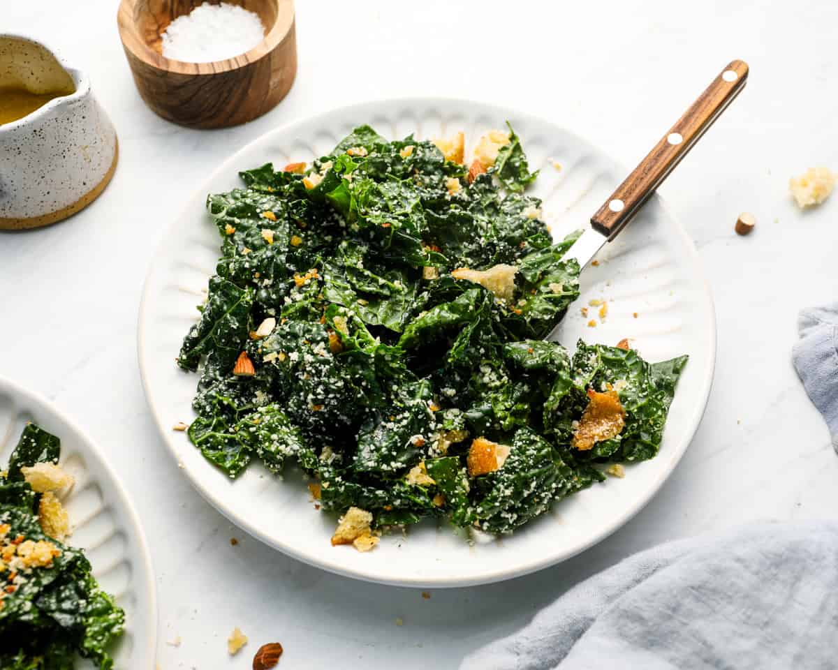 Kale salad plated with a serving fork, showcasing the texture of the greens, breadcrumbs, and toppings.