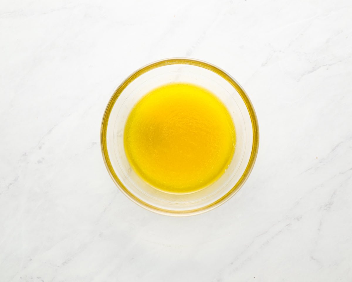 Bowl of freshly whisked lemon vinaigrette made with olive oil, lemon juice, Dijon mustard, maple syrup, and garlic.