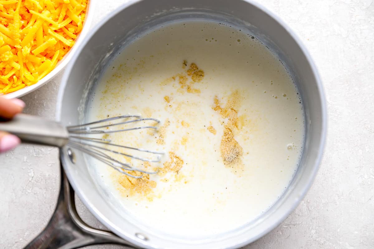 Seasonings sprinkled into the thickened milk mixture in the saucepan while whisking.