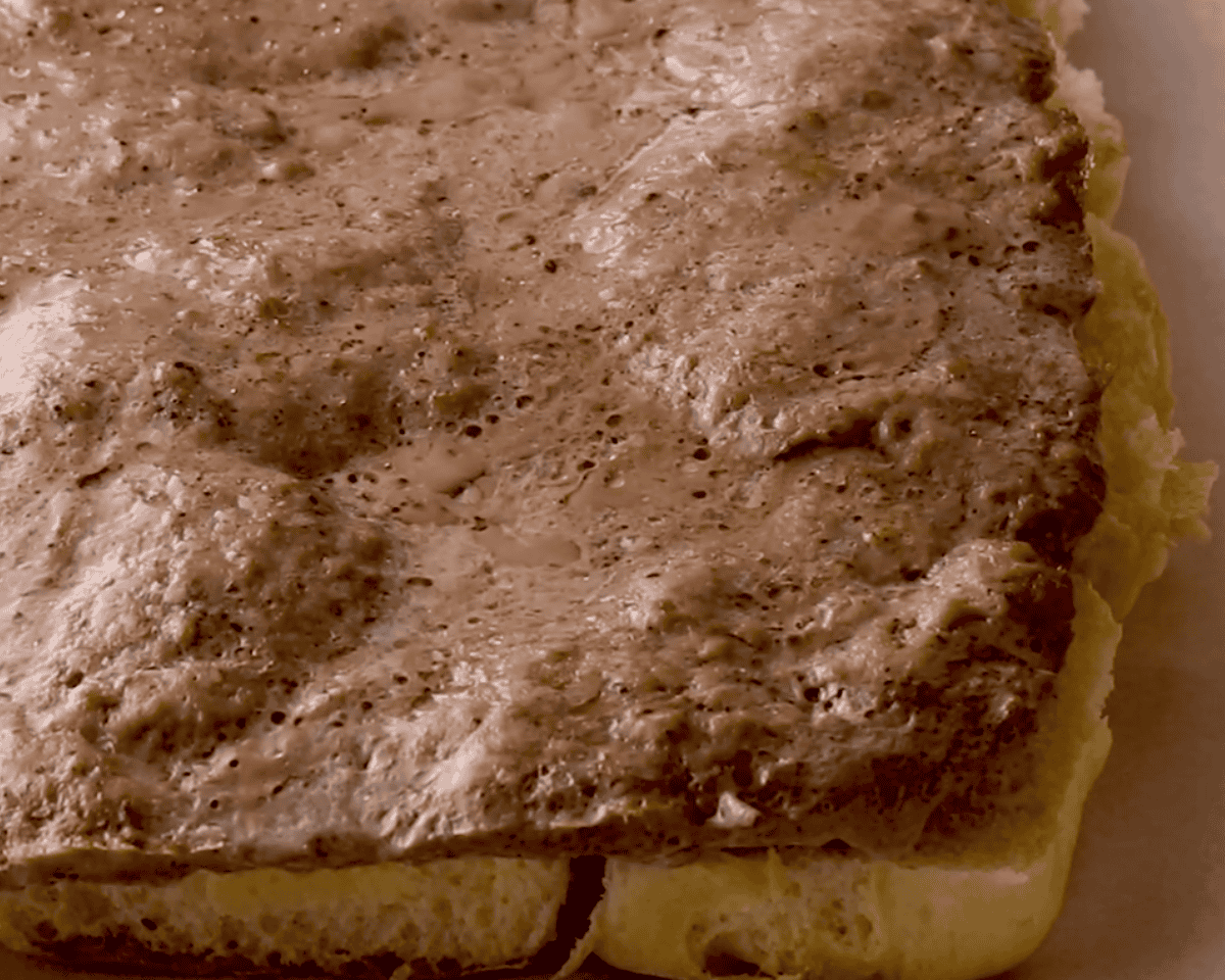 Cooked beef sitting on the bottom half of the rolls. 