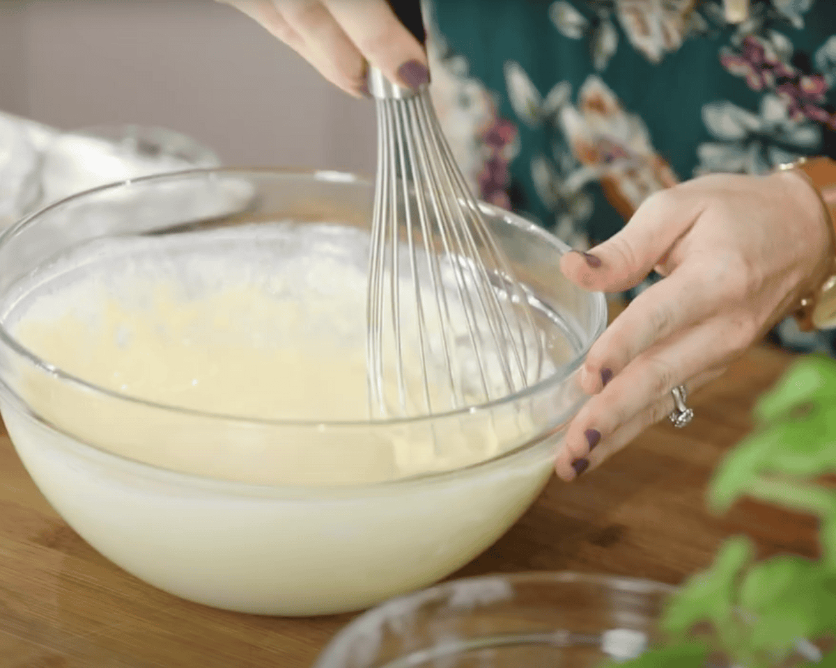 Mixing wet and dry ingredients until smooth in a clear glass bowl