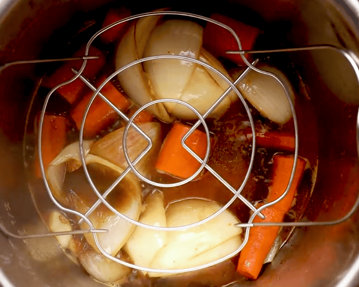 Trivet placed over the broth and vegetables inside the Instant Pot, ready for the roast.
