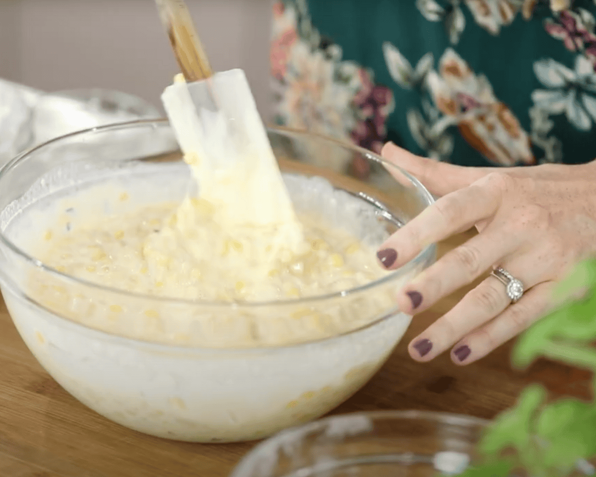 Folding corn kernels into the creamy pudding mixture with a spatula