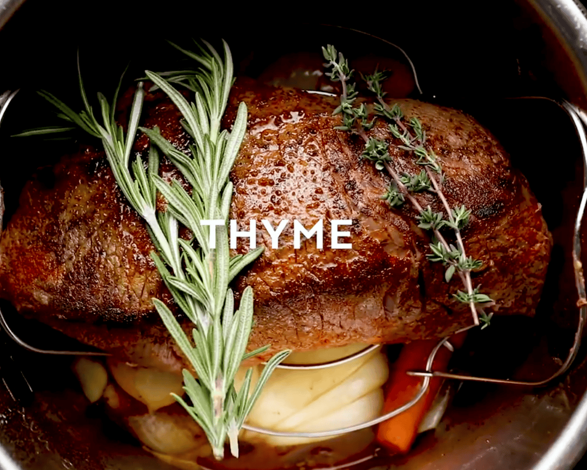 Seared roast placed on the trivet topped with fresh rosemary and thyme sprigs in the Instant Pot.