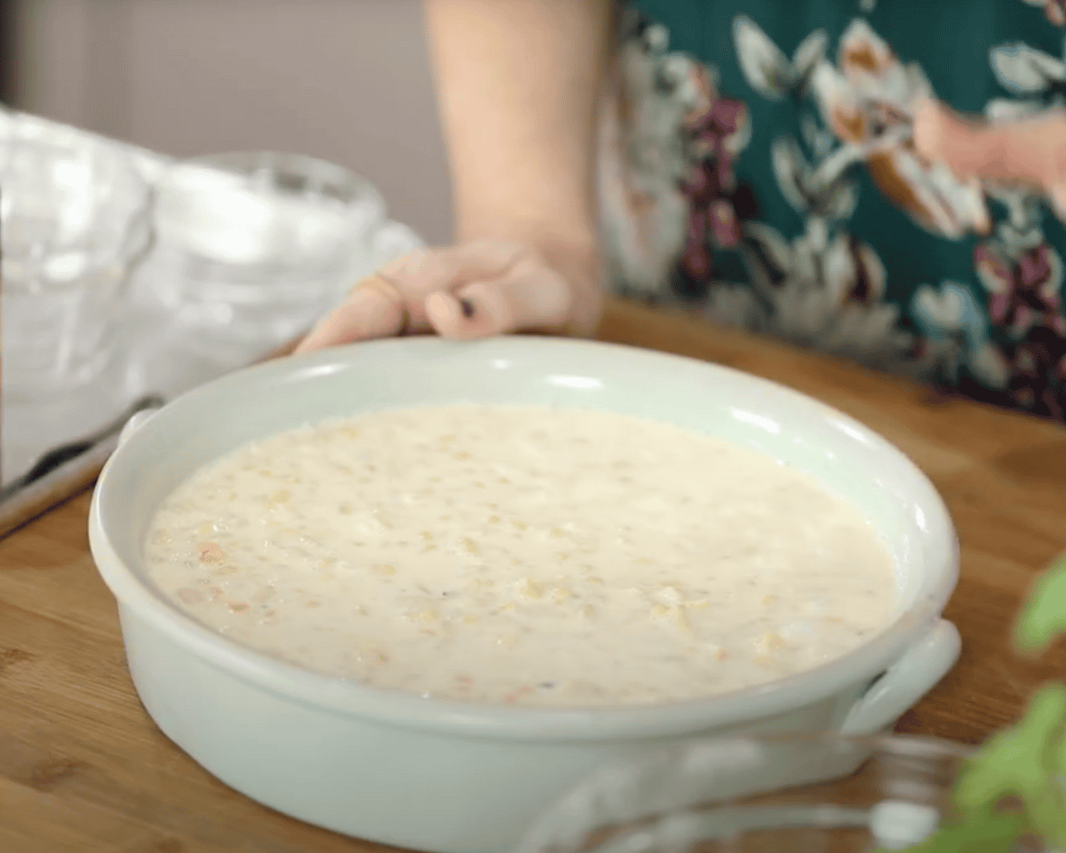 Unbaked corn pudding mixture poured into a round baking dish ready for the oven