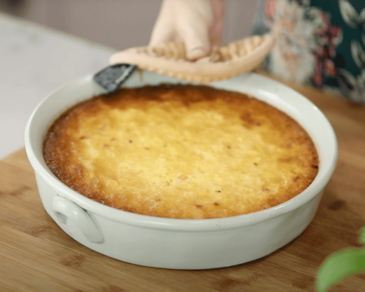 Golden baked corn pudding fresh out of the oven in a white round casserole dish