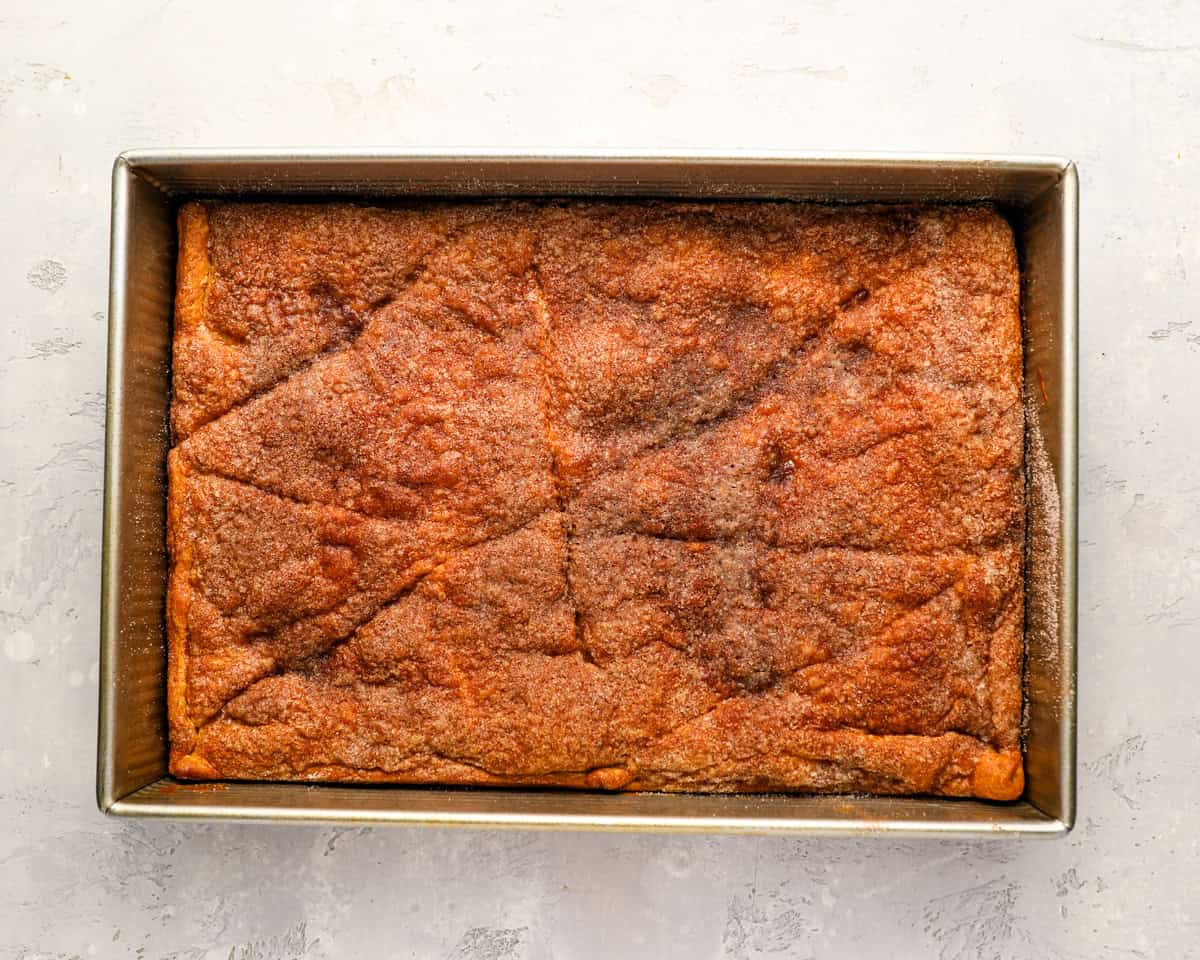 A fully baked churro cheesecake in a 9x13 pan with a golden, cinnamon sugar crust.