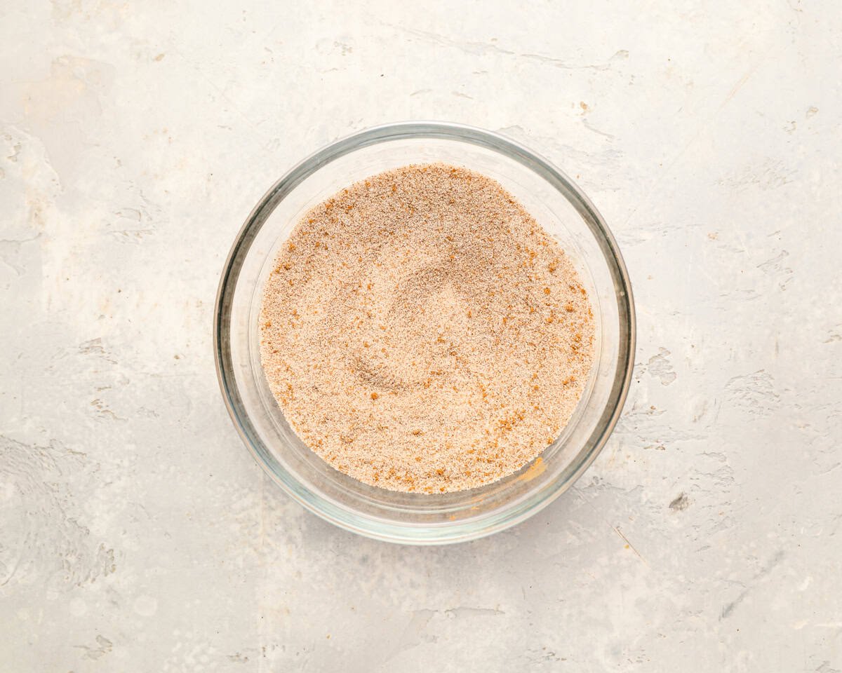 A glass bowl filled with cinnamon sugar mixture on a light countertop.