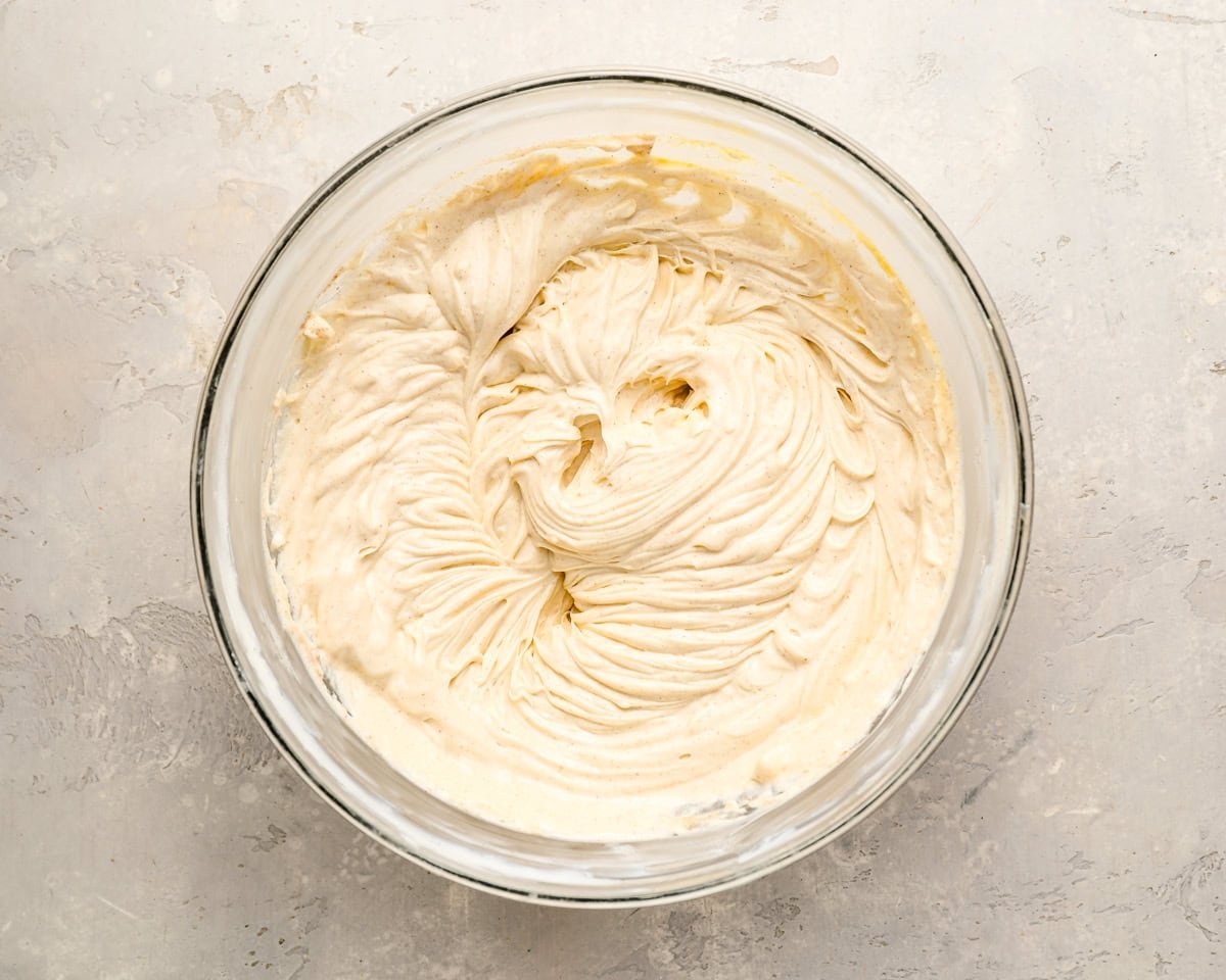 A mixing bowl filled with smooth, whipped cream cheese cheesecake filling.