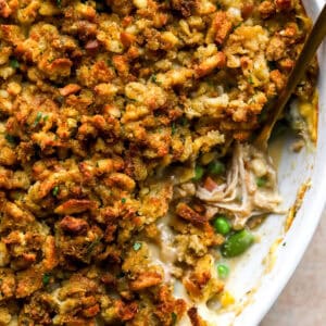 Close-up of baked chicken stuffing casserole in a white dish with a golden, crispy stuffing topping and creamy chicken filling underneath.