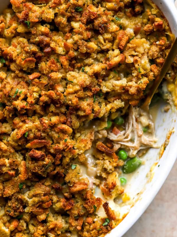 Close-up of baked chicken stuffing casserole in a white dish with a golden, crispy stuffing topping and creamy chicken filling underneath.
