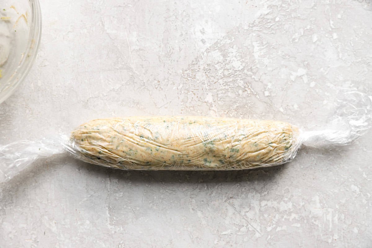 Cowboy butter shaped into a log and tightly wrapped in plastic wrap before chilling.