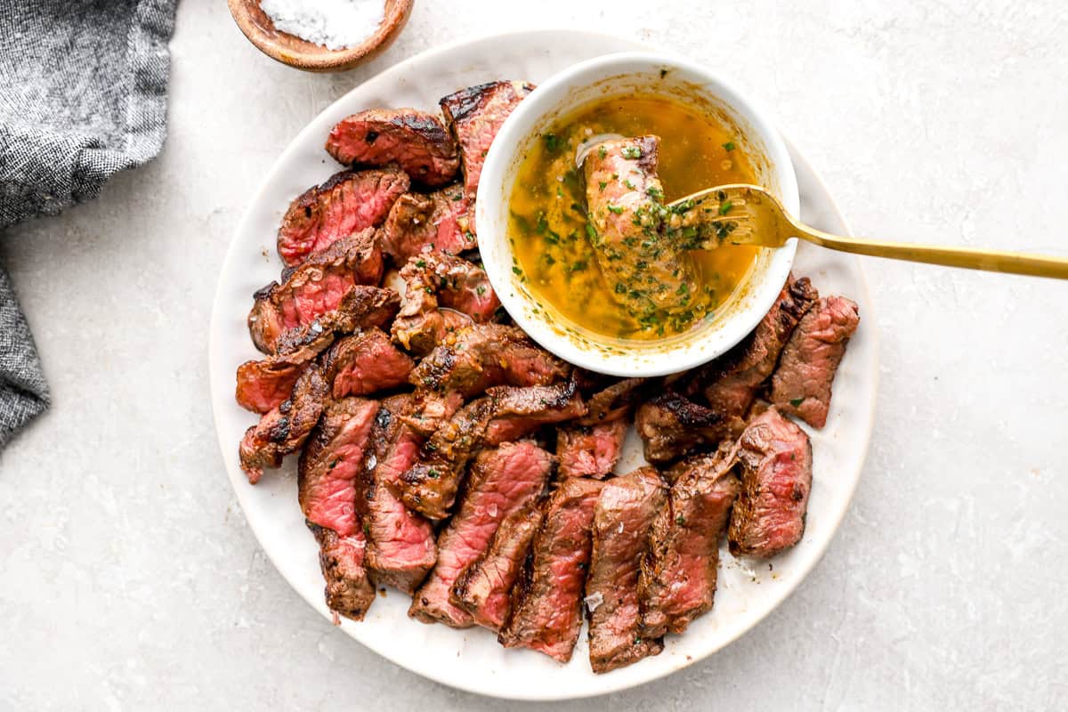 Sliced steak bites served with a small bowl of melted cowboy butter for dipping.