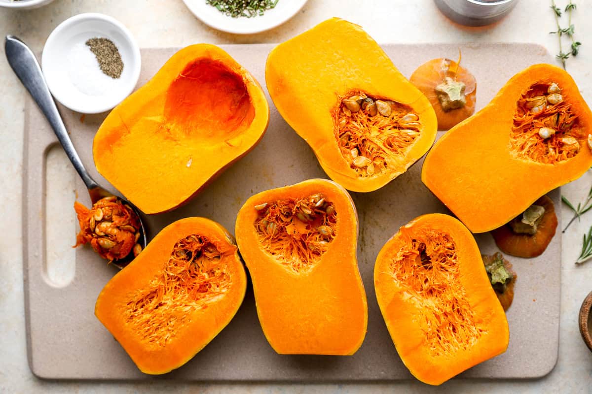 Honeynut squash cut in half on a cutting board with seeds scooped out, ready for roasting.