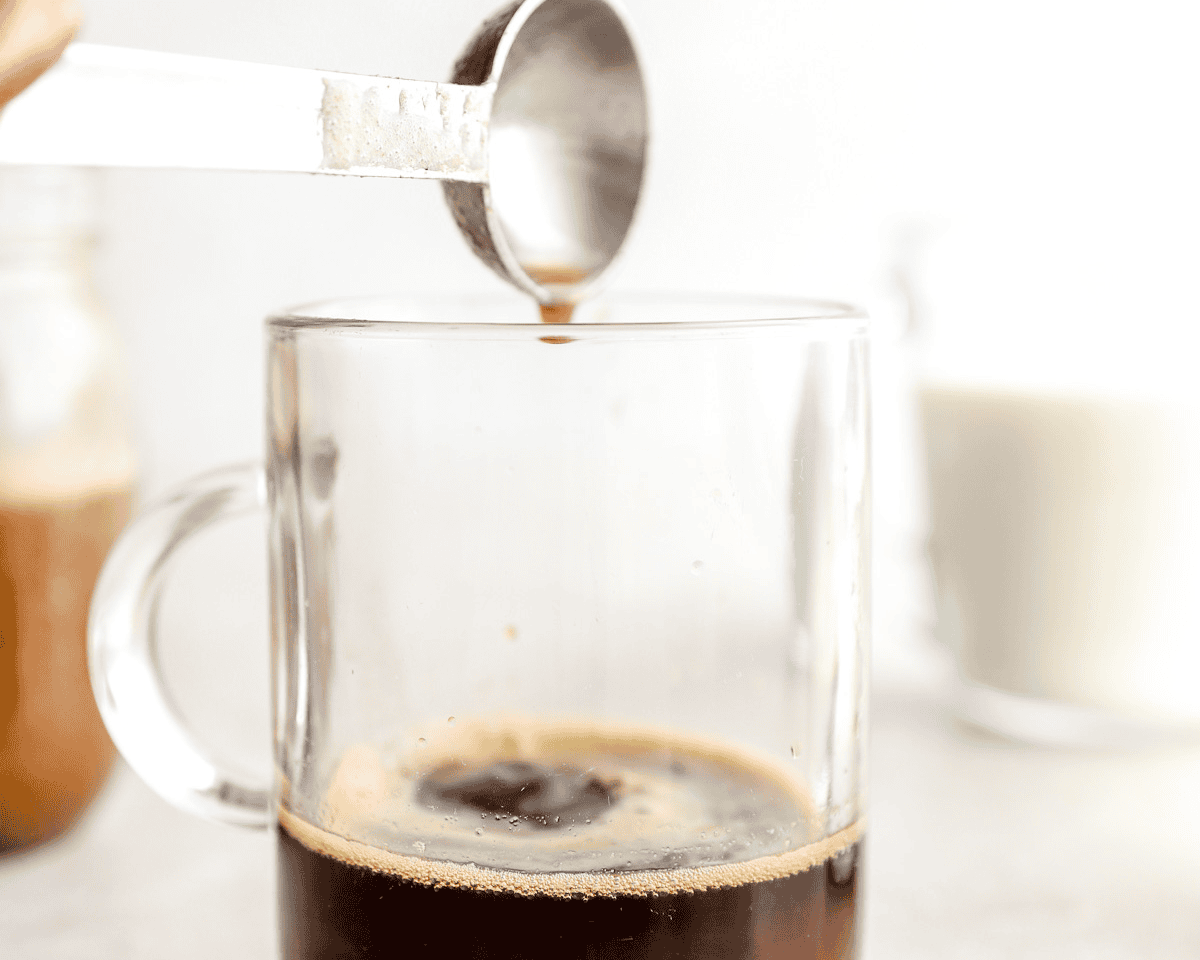 Banana syrup being measured and poured into freshly brewed espresso