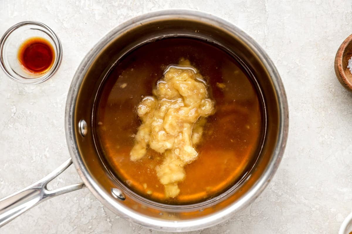 Mashed ripe banana simmering with brown sugar and water in a saucepan to make banana syrup