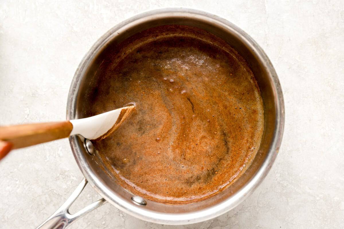 Cinnamon being stirred into the banana syrup as it simmers in a saucepan