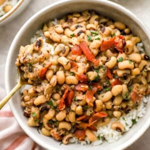 Bowl of Southern-style black-eyed peas with bacon served over white rice and garnished with fresh parsley