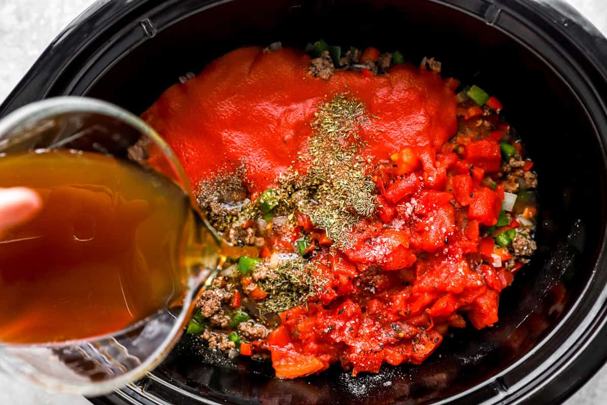 Tomatoes, broth, and seasonings added to the crockpot for stuffed pepper soup