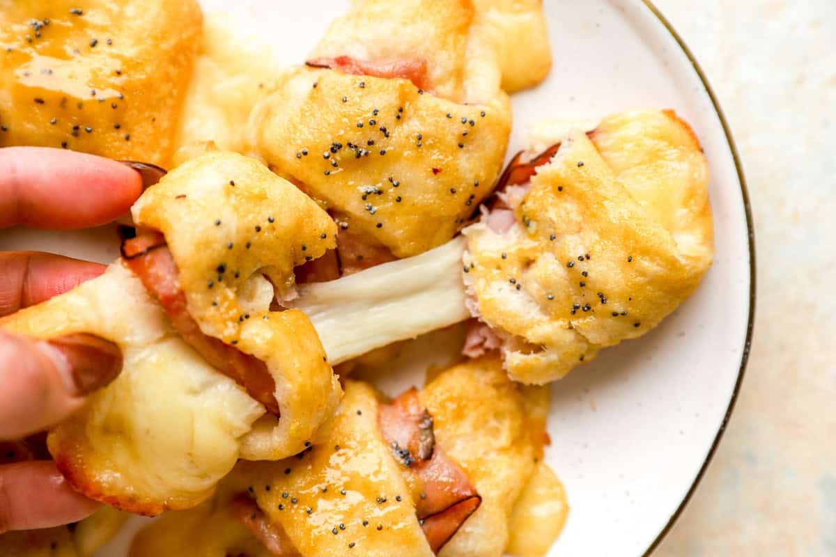 plate of ham and cheese croissants and hand pulling one