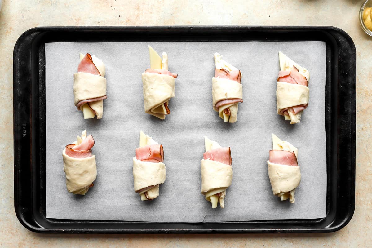 unbaked ham and cheese croissants on a baking sheet
