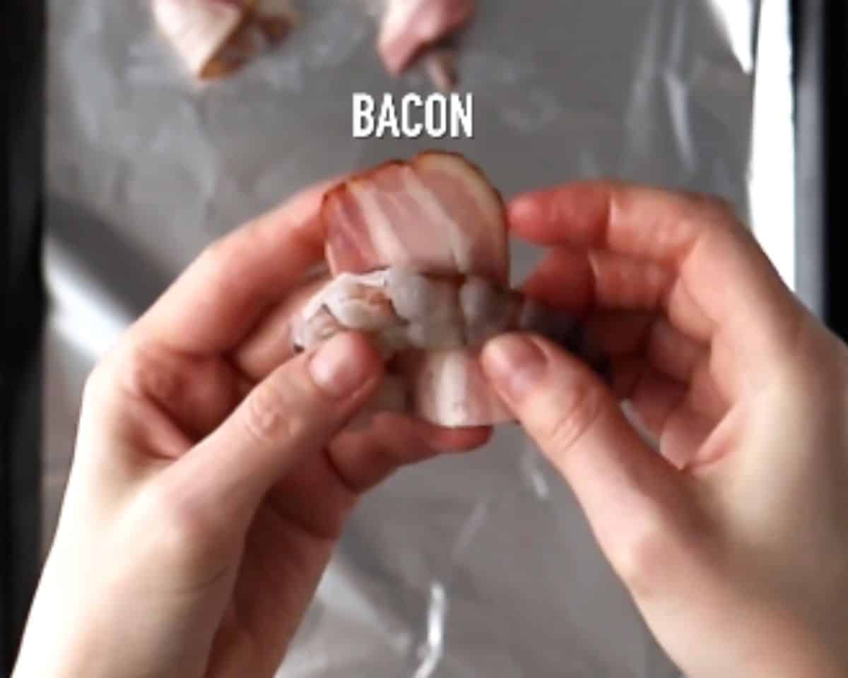 Raw shrimp being wrapped tightly with a third slice of thick bacon and secured with a toothpick. - 6