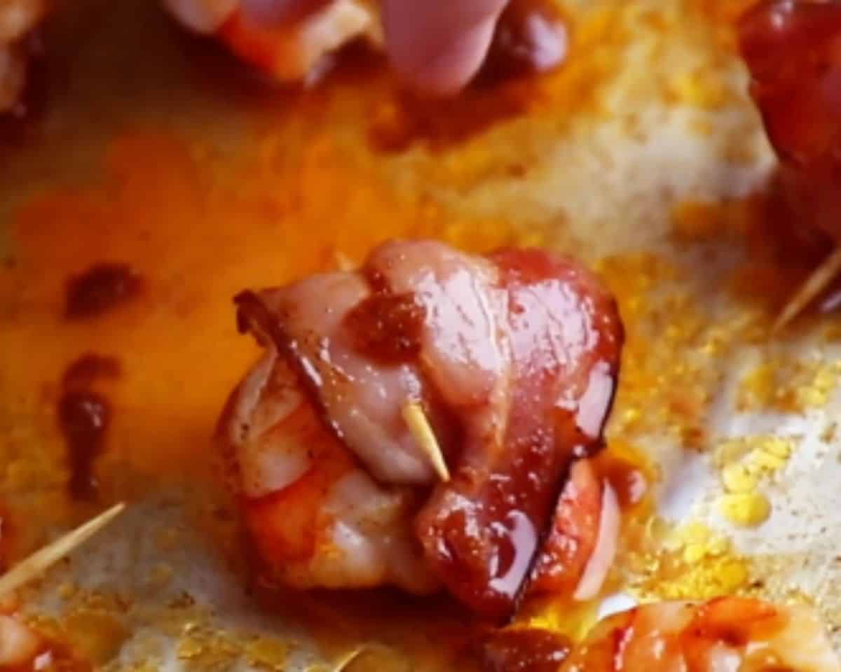 Close up of bacon wrapped shrimp coated in sticky brown sugar glaze on the baking sheet before baking. - 9