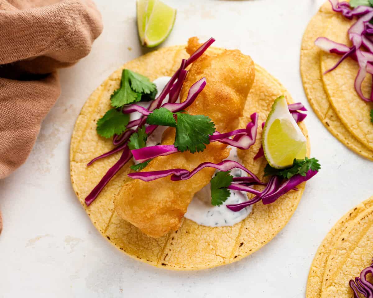 Crispy beer battered fish taco topped with purple cabbage, fresh cilantro, and a squeeze of lime.