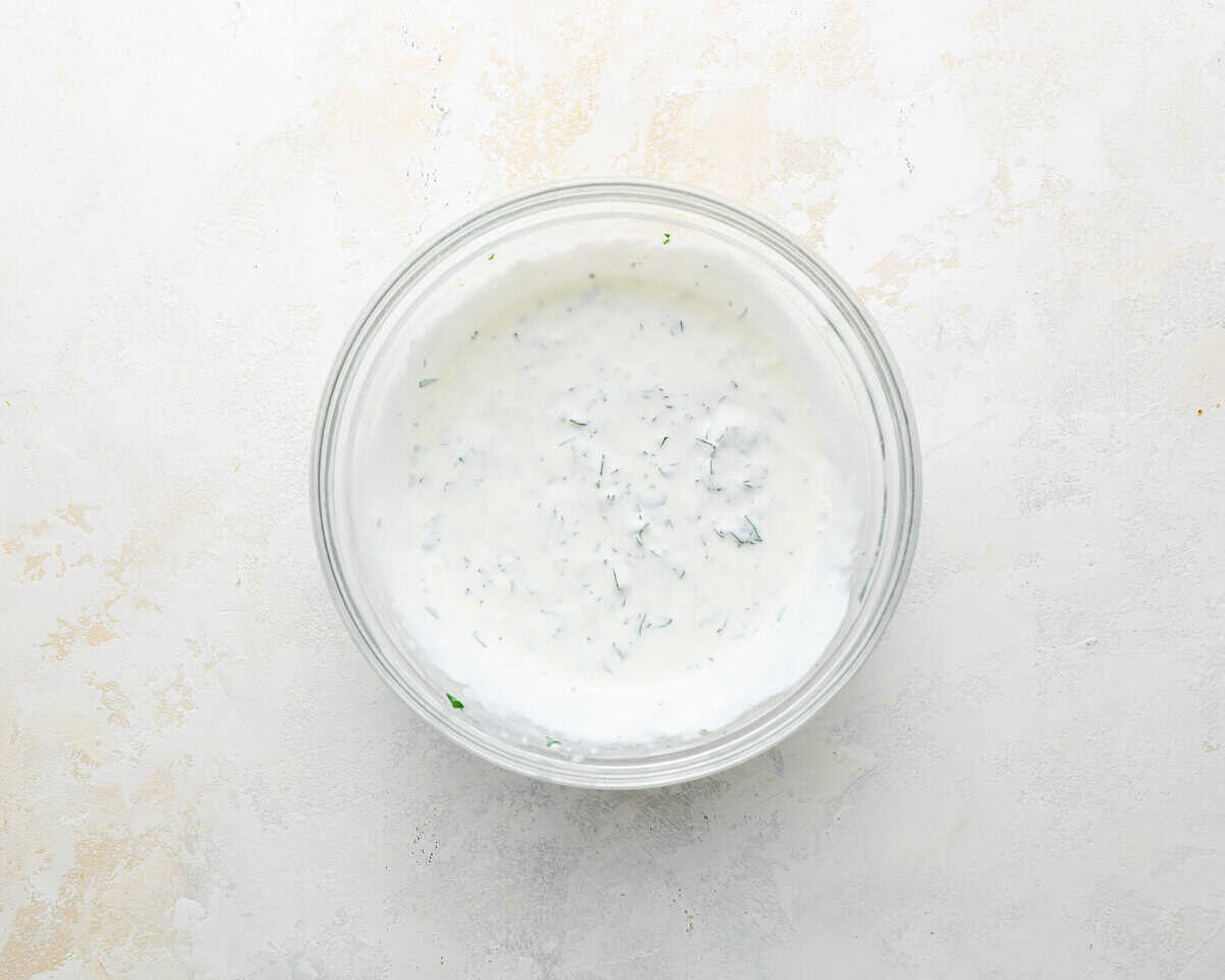 Creamy cilantro lime crema in a glass bowl, ready to drizzle over fish tacos.