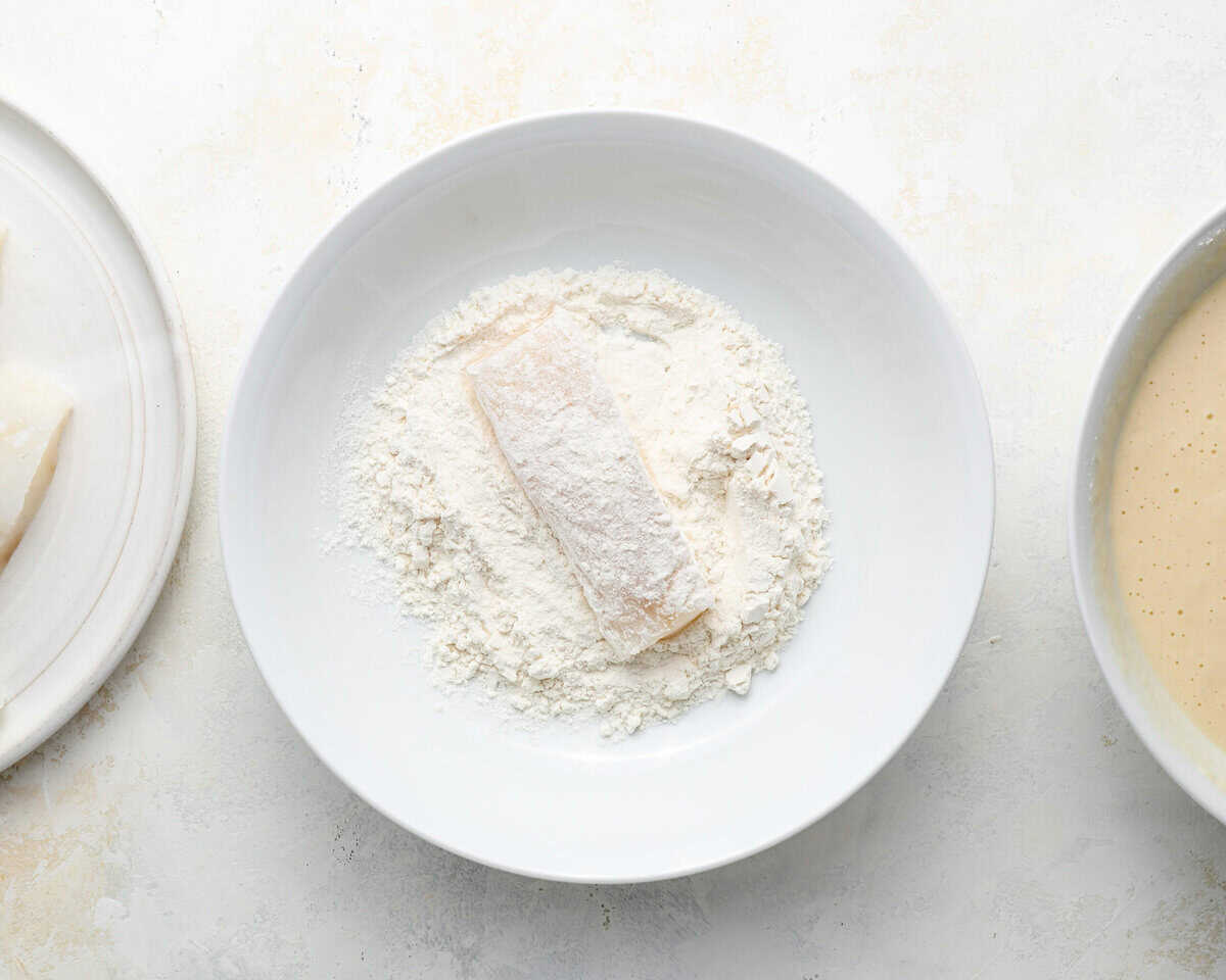 Piece of cod lightly dredged in flour before dipping into beer batter.