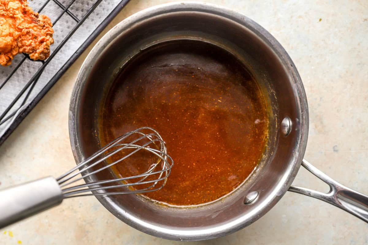 Hot honey sauce whisked together in a saucepan with butter and spices.