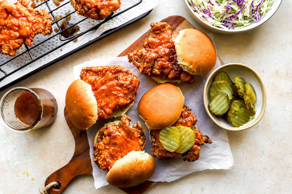 Hot honey chicken sliders assembled on brioche buns with pickle chips and sauce.