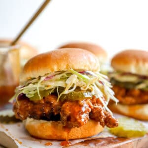 Crispy hot honey chicken slider on a toasted brioche bun topped with creamy coleslaw and pickle chips.