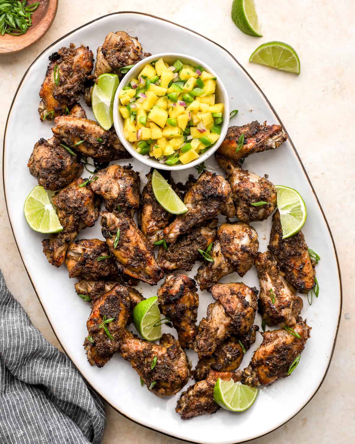 Platter of oven baked jerk chicken wings served with pineapple salsa and lime wedges