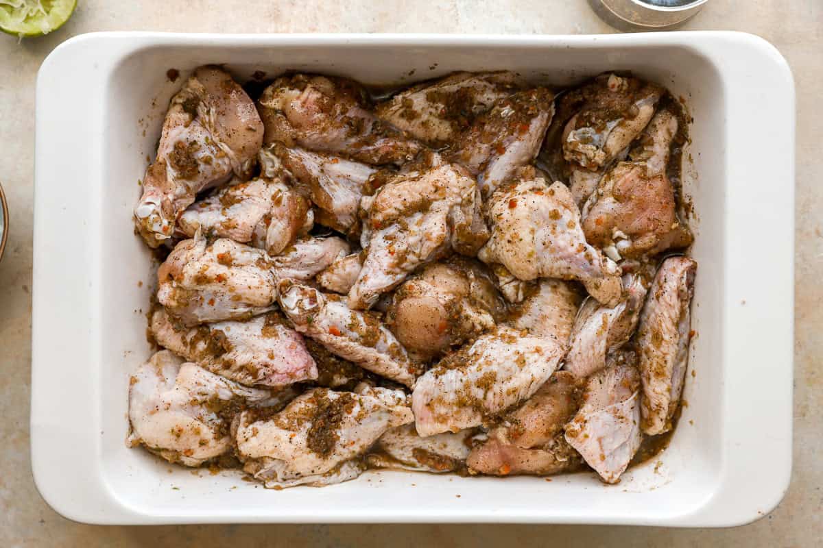 Raw chicken wings marinating in homemade jerk sauce in a baking dish