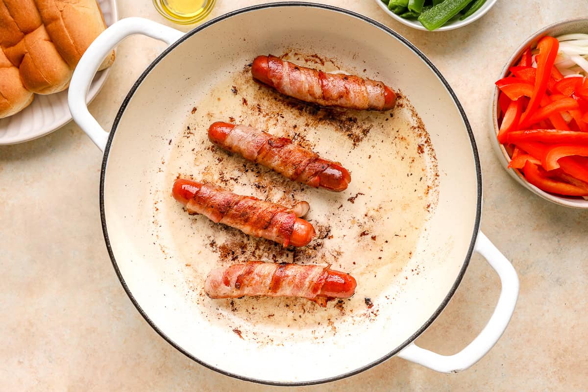 bacon wrapped hot dogs cooking in pan