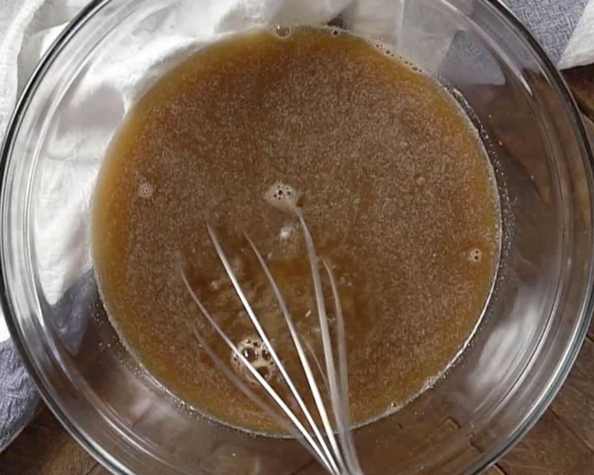 Beef broth mixture with bouillon, garlic, Worcestershire sauce, and mustard whisked together in glass bowl