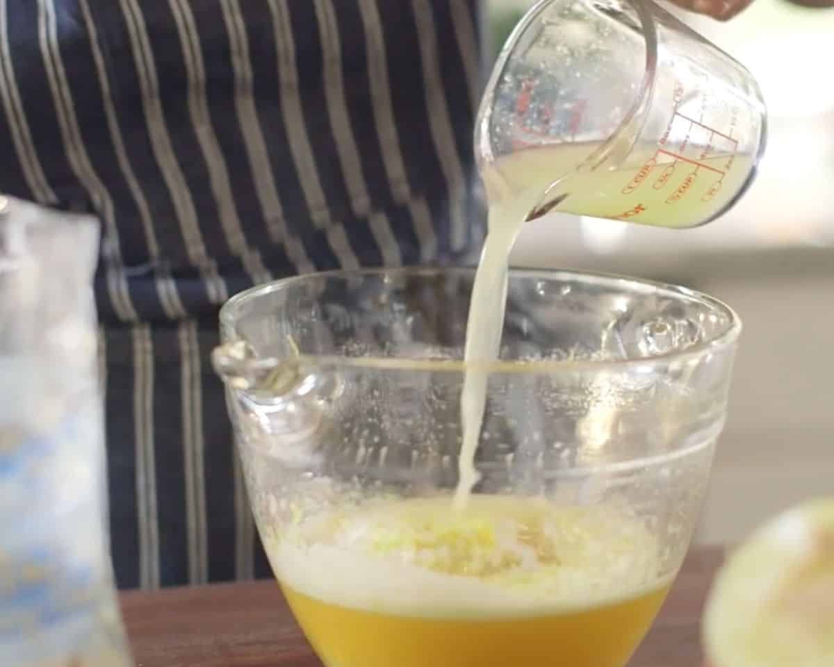 Fresh lemon juice being poured into bowl to make lemon bar filling