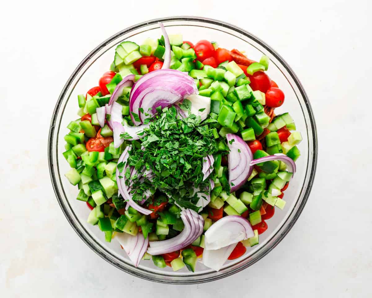 Chopped tomatoes, cucumber, green bell pepper, red onion, parsley, cheddar, and pepperoni added to the spaghetti