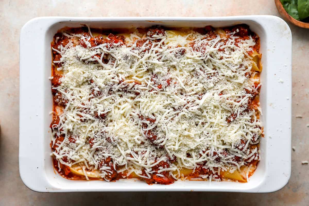 Italian stuffed shells topped with cheese and ready to be baked