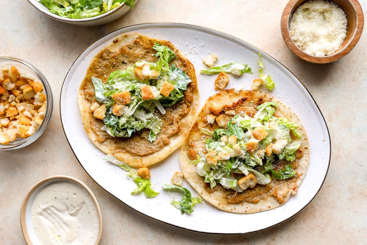 Chicken Caesar smash tacos topped with romaine lettuce, croutons, parmesan cheese, and Caesar dressing.