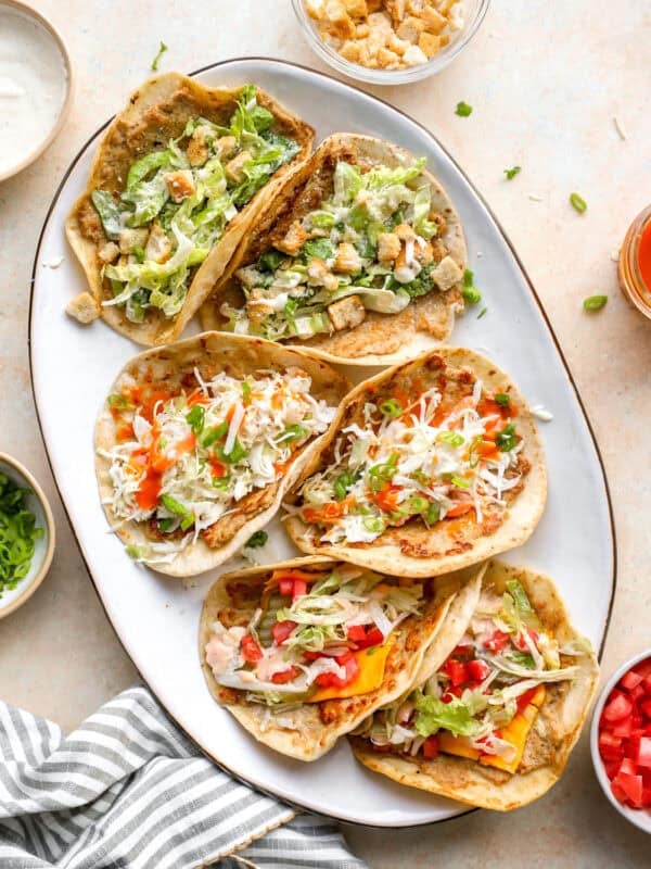 Chicken smash tacos three ways on a serving platter with Caesar, buffalo chicken, and cheeseburger toppings.