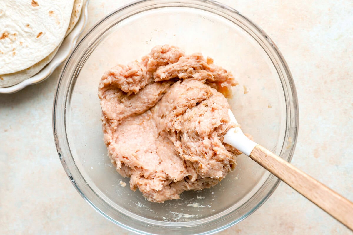 Seasoned ground chicken mixture in a glass bowl for making chicken smash tacos.