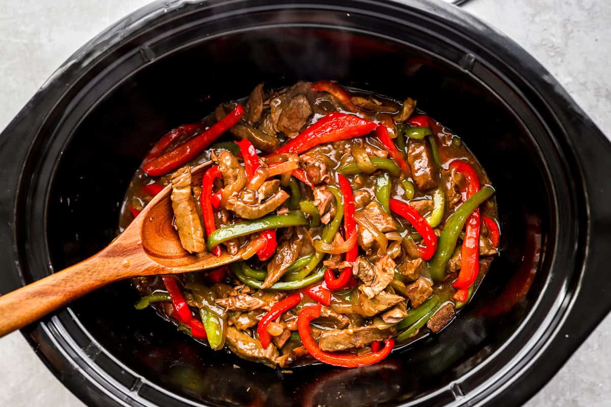 Tender crockpot pepper steak with bell peppers and onions in a rich savory sauce.